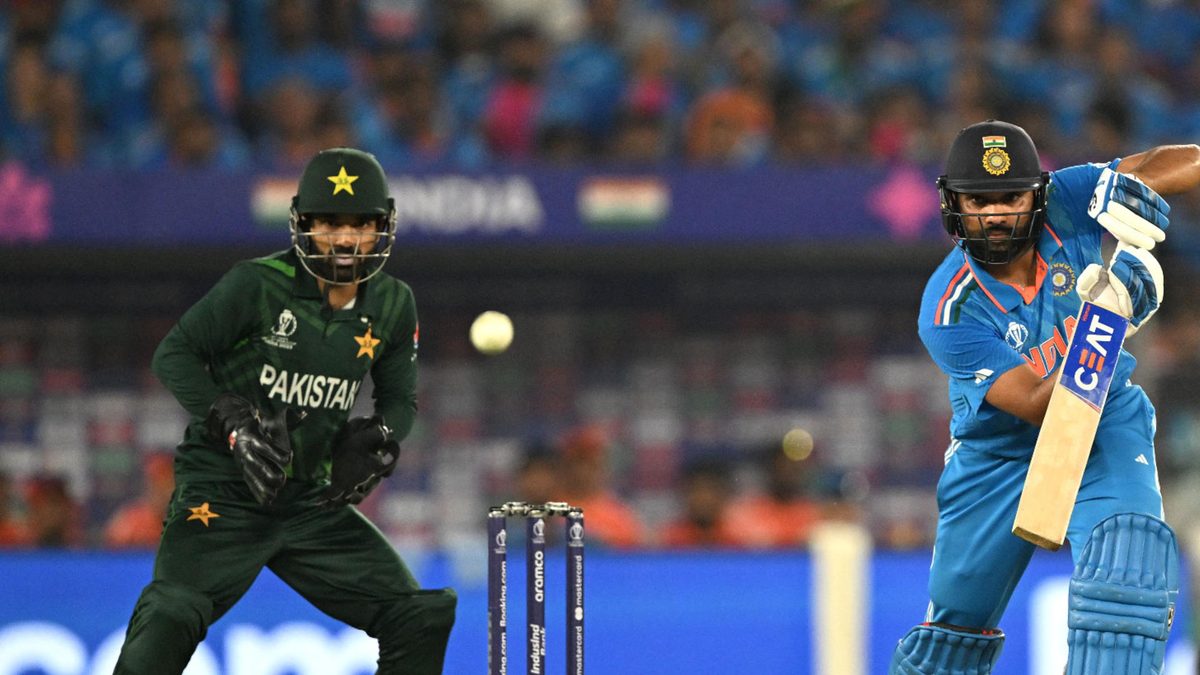 India's captain Rohit Sharma (R) plays a shot as Pakistan's wicketkeeper Mohammad Rizwan watches during the 2023 ICC Men's Cricket World Cup one-day international (ODI) match between India and Pakistan at the Narendra Modi Stadium in Ahmedabad on October 14, 2023