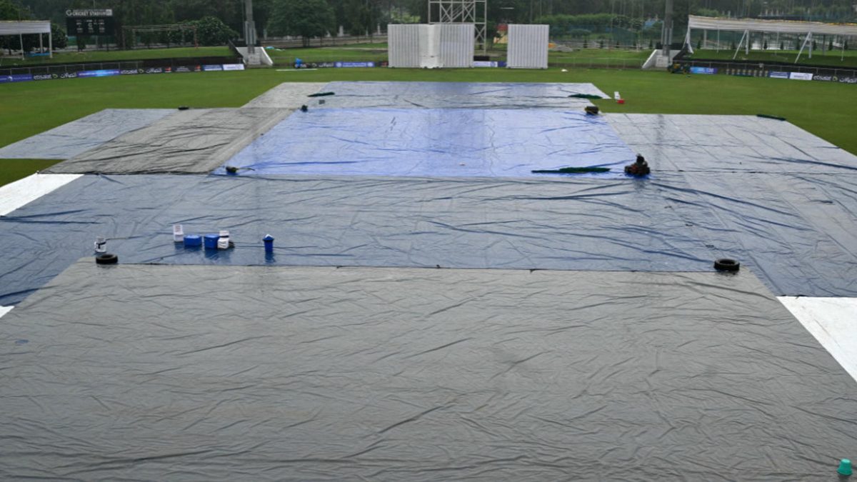 Groundsmen cover the field as it starts to rain on the eve of one-off Test cricket match between Afghanistan and New Zealand at the Shaheed Vijay Singh Pathik Sports Complex in Greater Noida on September 8, 2024