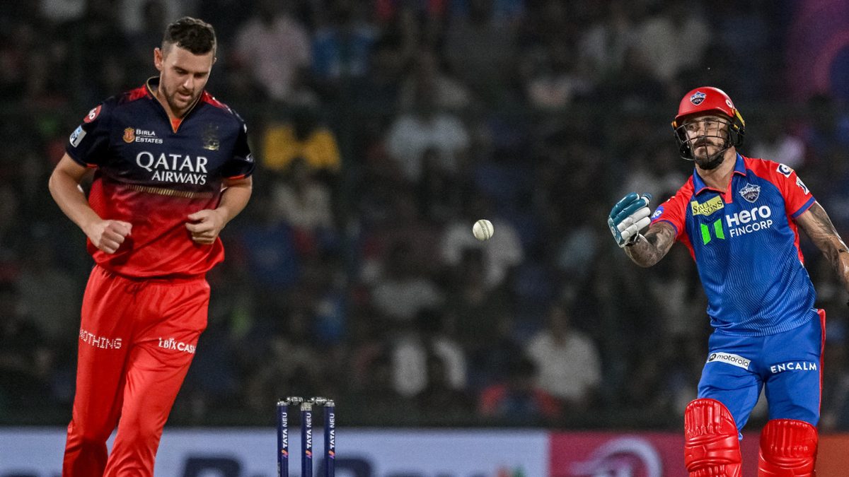 Delhi Capitals' Faf du Plessis (R) throws the ball as Royal Challengers Bengaluru's Josh Hazlewood walks back to bowl during the Indian Premier League (IPL) Twenty20 cricket match between Delhi Capitals and Royal Challengers Bengaluru at the Arun Jaitley Stadium in New Delhi on April 27, 2025