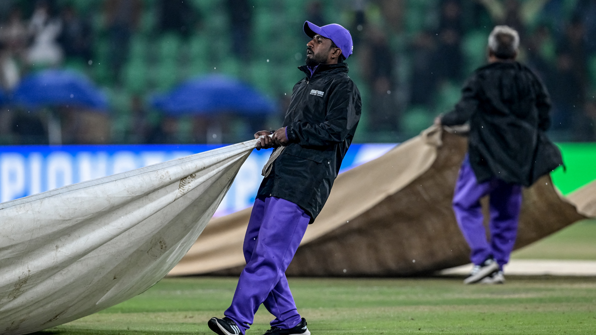 Groundsmen cover the pitch as rain stops play